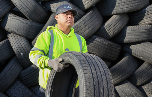 An employee lifts a tire to load it in a truck